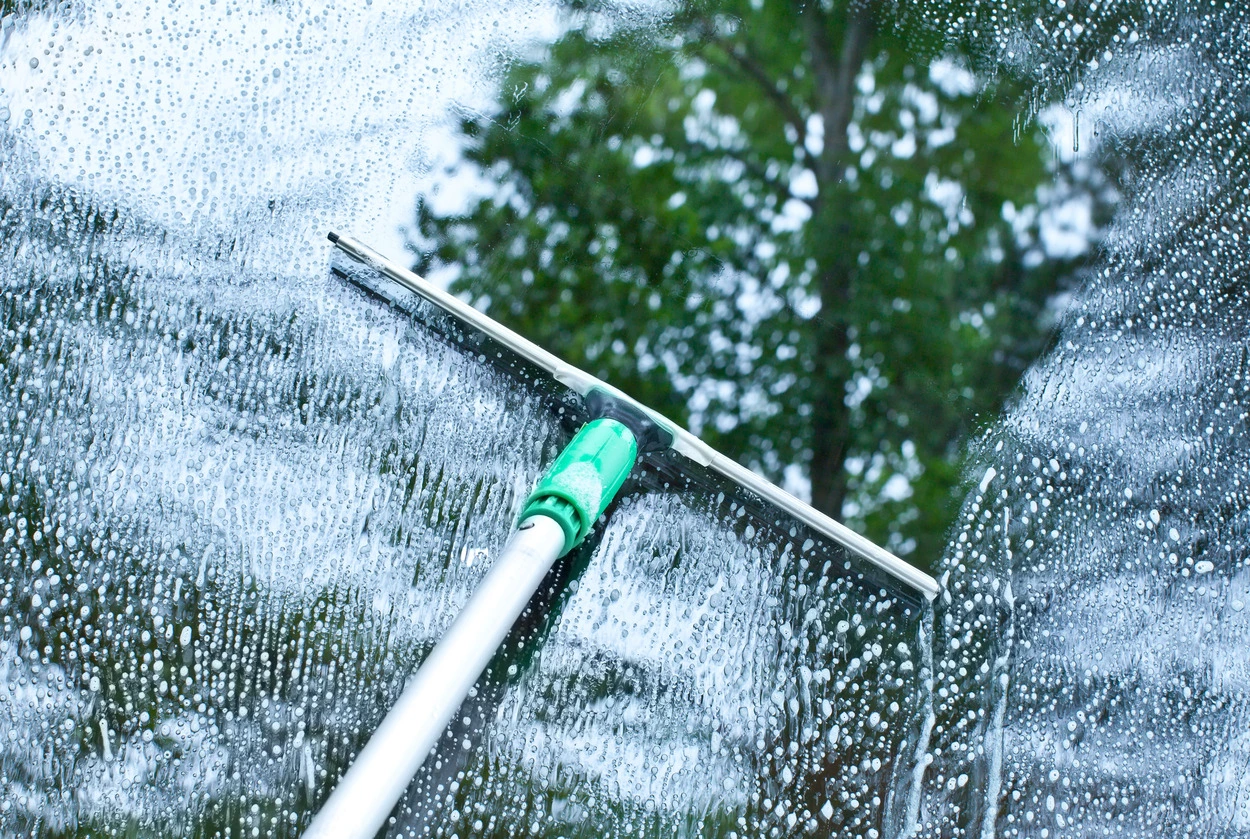 Professional window cleaner using a squeegee on a residential window in Lodi, CA